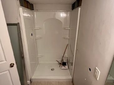 A bathroom with a shower stall and a mop in it.