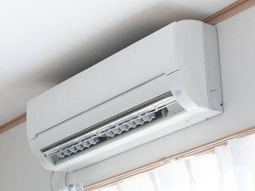 A white air conditioner is hanging from the ceiling in a room.