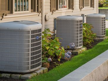 An air conditioner is sitting outside of a house next to a window.