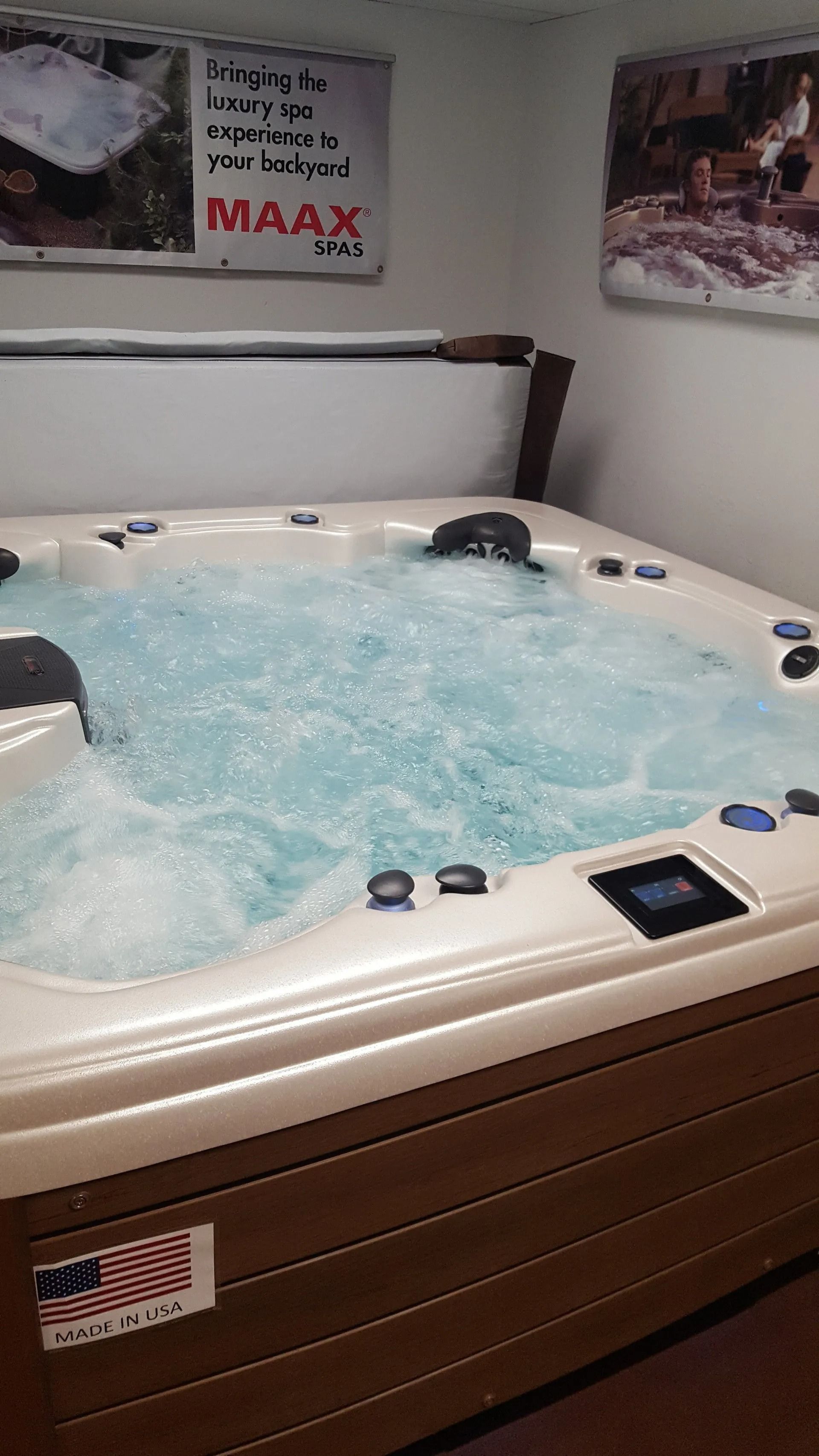 A bubbling hot tub in a room, with a partially open cover. It is brown and white.