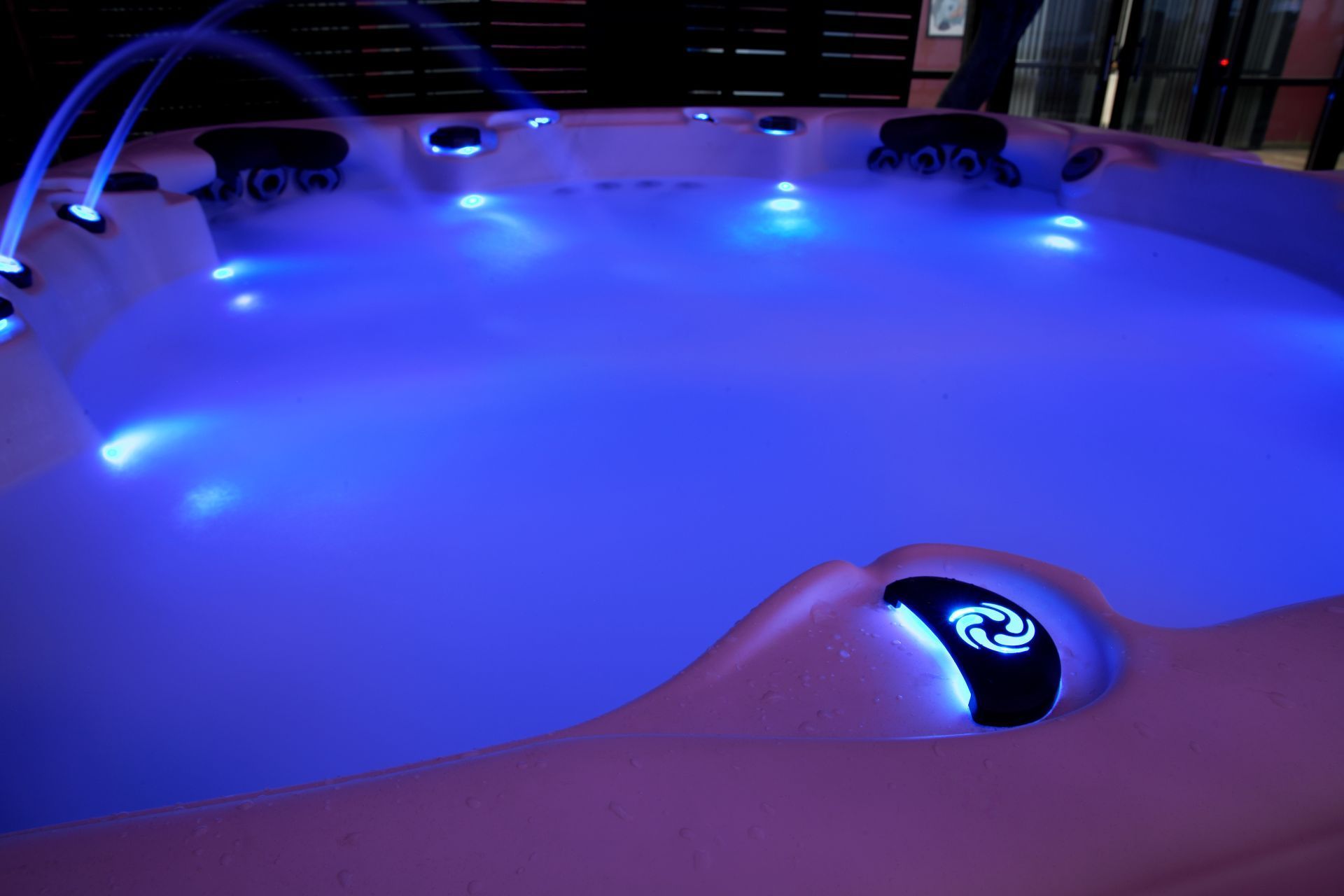 Lit hot tub with blue underwater lights and water jets.