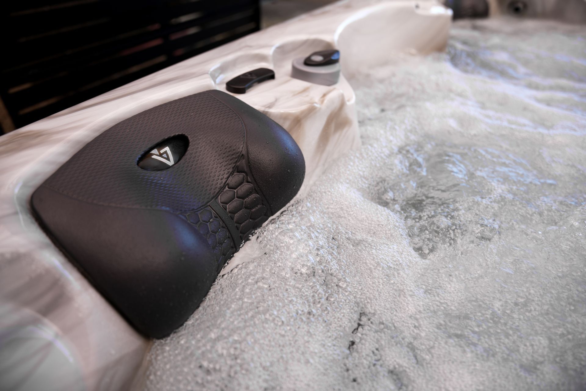 Close-up of a hot tub with bubbly water and a black control panel with buttons.