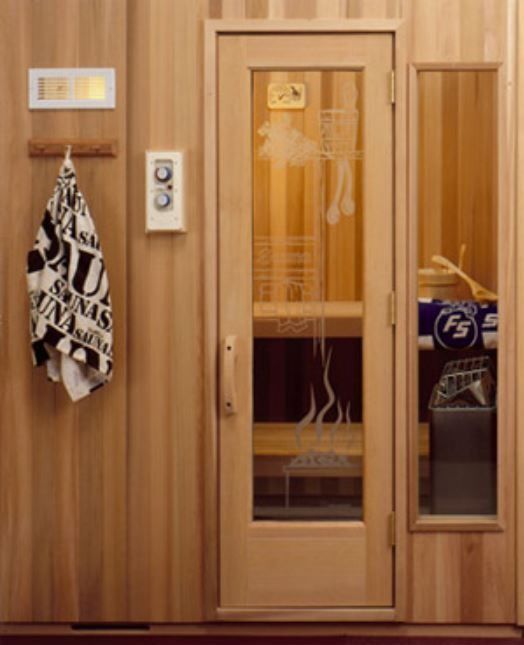 Sauna interior: wood-paneled walls, glass door with etched design, towel, control panel, and small window.
