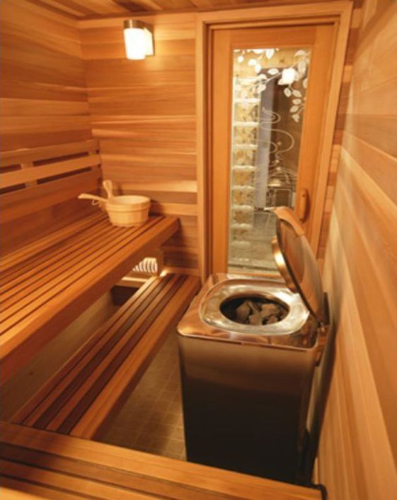 Wooden sauna with benches, a bucket, and a heater; glass-block door visible.