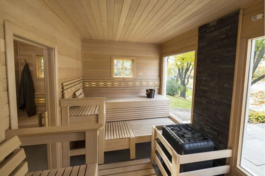 Wooden sauna with benches, a window, and a heater, in a home.