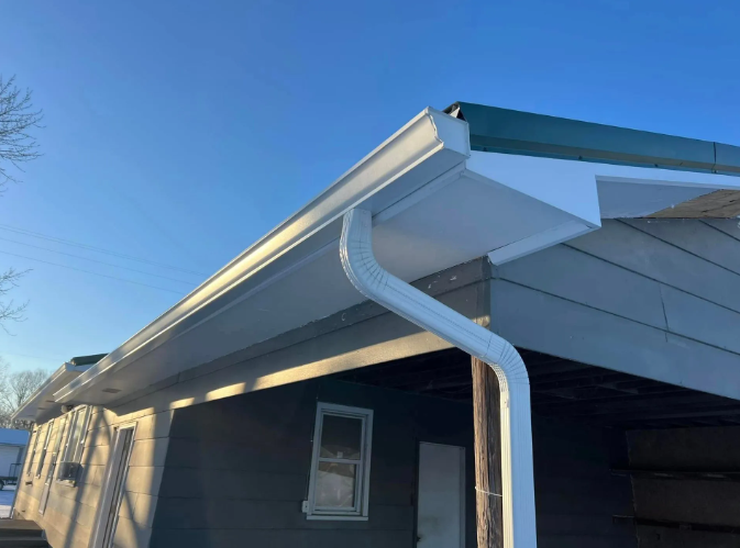 White gutters along a house under a clear, blue sky.