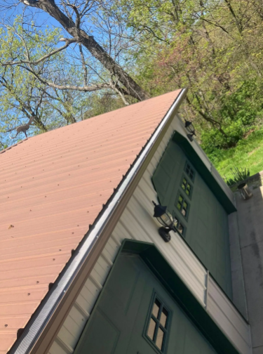 Brown metal roof on a green building with small windows and a black light fixture.