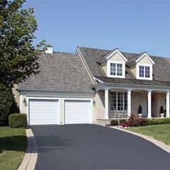 a large house with two garage doors and a driveway leading to it