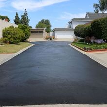 a black asphalt driveway leading to a house in a residential neighborhood