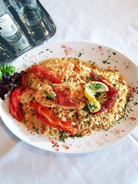 A plate of food on a table with a bottle of water in the background