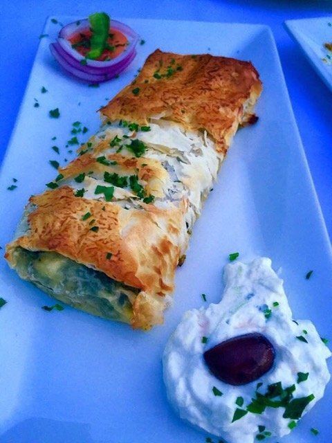 A white plate topped with a wrap and a dip