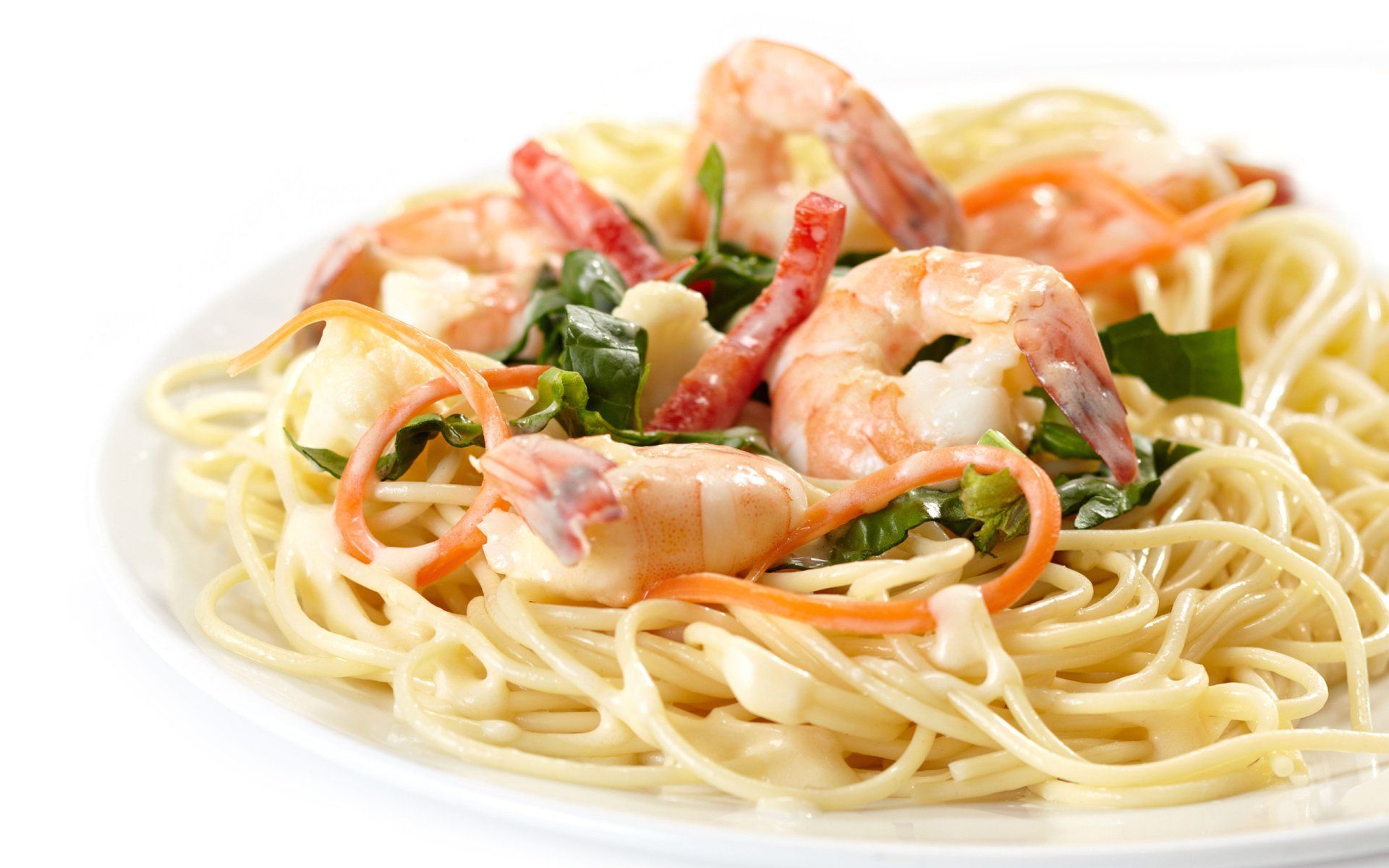 A white plate topped with noodles and shrimp on a white background.