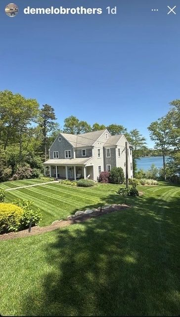 White house with manicured lawn and lake view under a clear blue sky