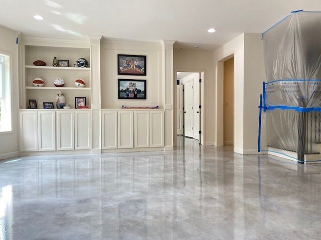 Polished concrete floor in a room with white built-in cabinets and neutral walls.
