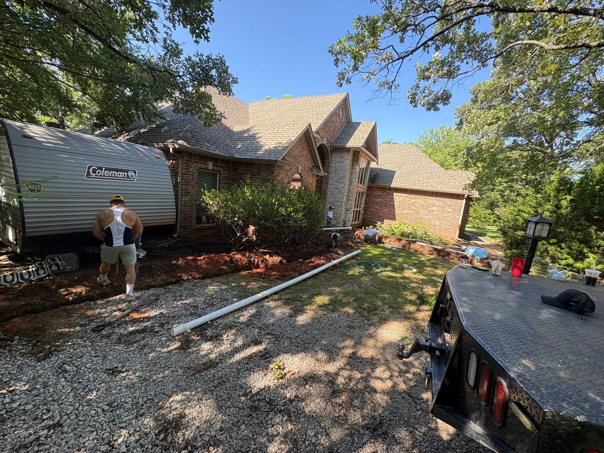 A trailer near a house, and a man is walking beside it on gravel.