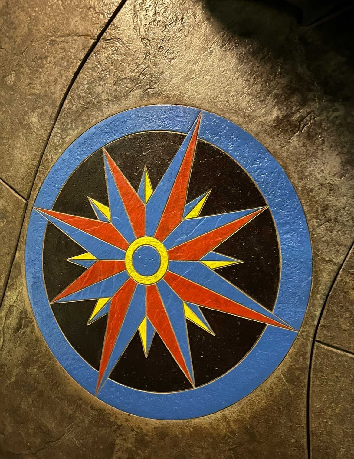 Compass rose design in blue, red, and yellow on a dark floor.