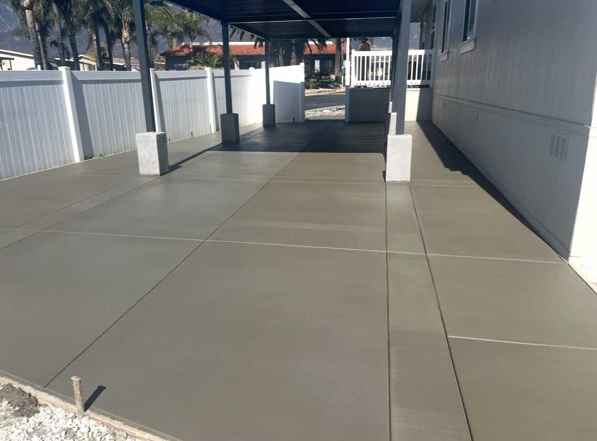 Newly poured gray concrete driveway with a covered carport area.