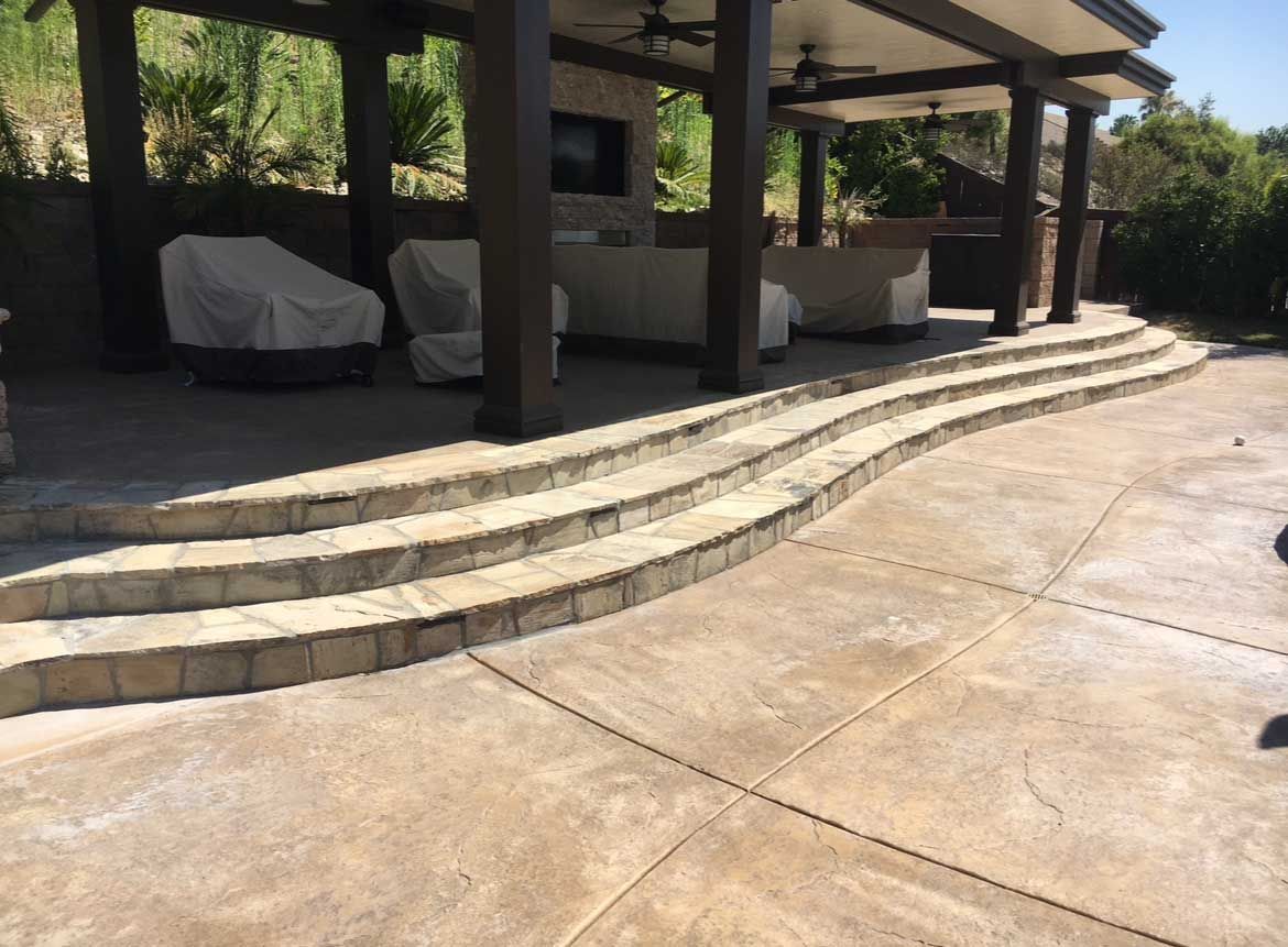 Outdoor stone steps leading up to a covered patio with furniture.