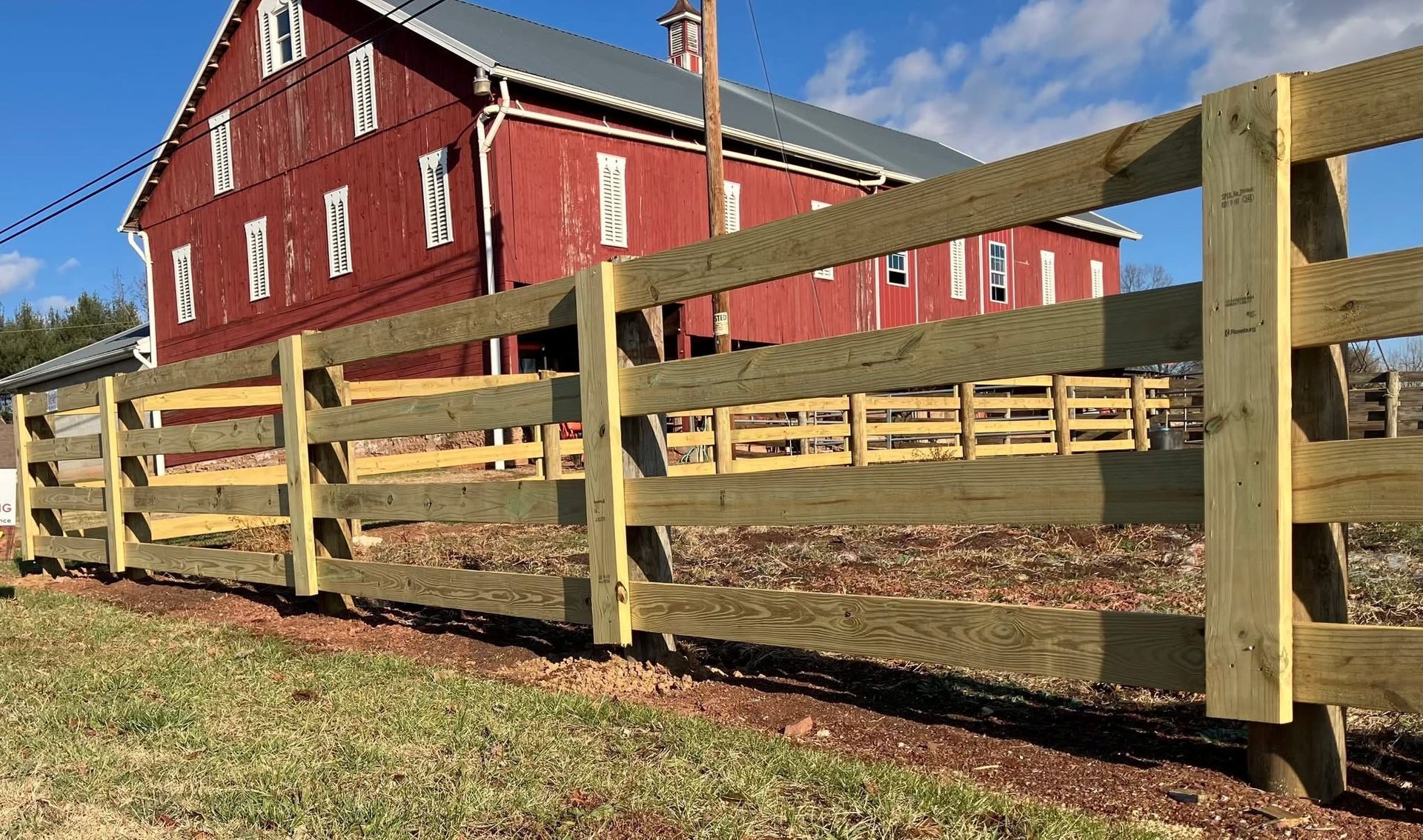 A wooden fence with a red barn in the background