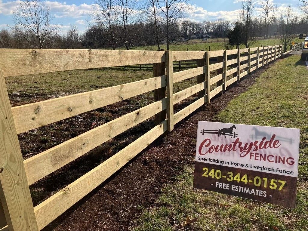 A wooden fence in a field with a sign for countryside fencing.