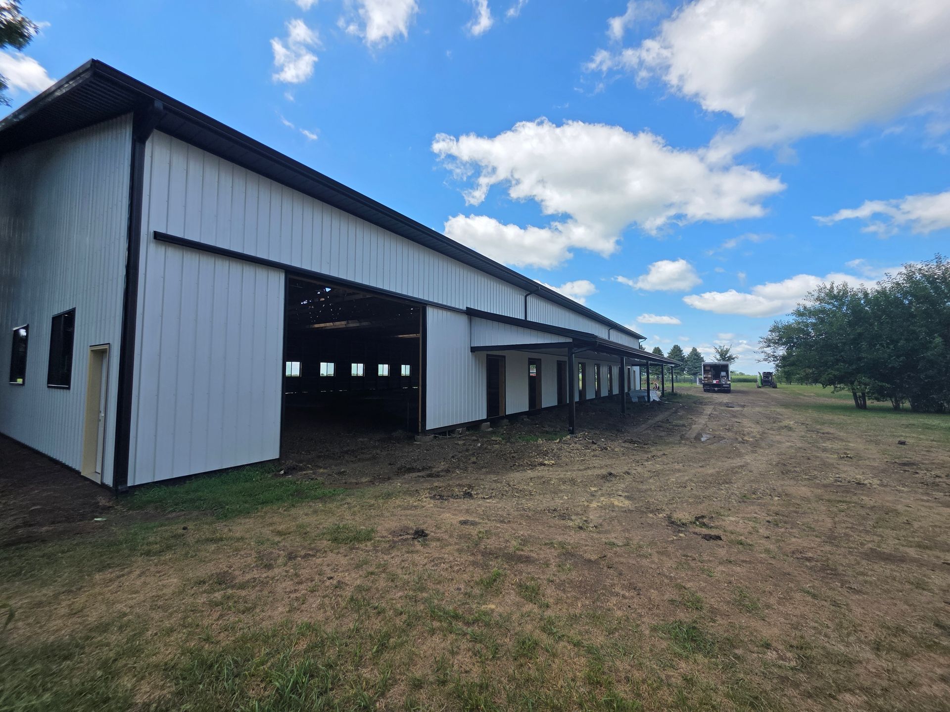 White barn with black trim under a blue sky with clouds.