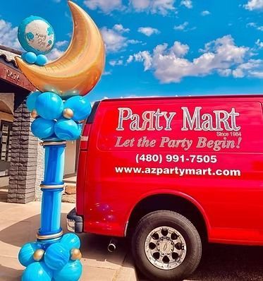 A red party mart van is parked in front of a building