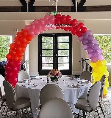 A room with tables and chairs and a balloon arch that says azpartymart