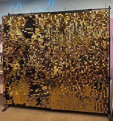 A large gold sequined wall is sitting on the floor in a room.