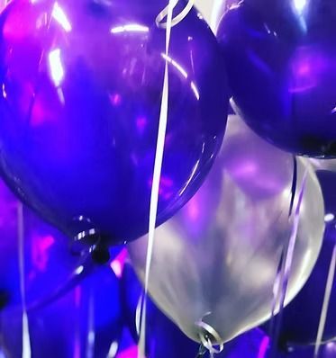 A bunch of purple and white balloons are floating in the air
