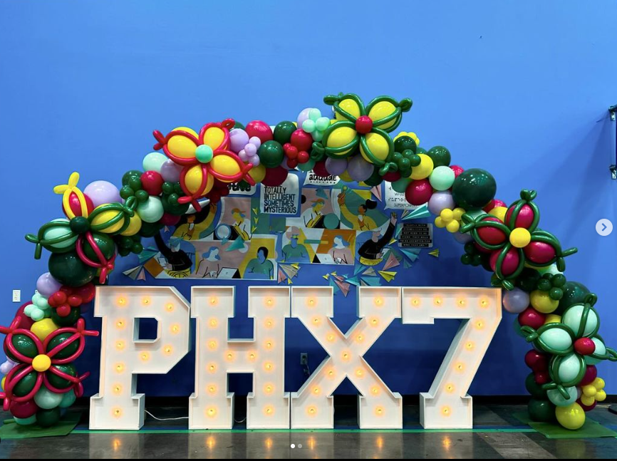 A large sign that says PHX7 is surrounded by balloons