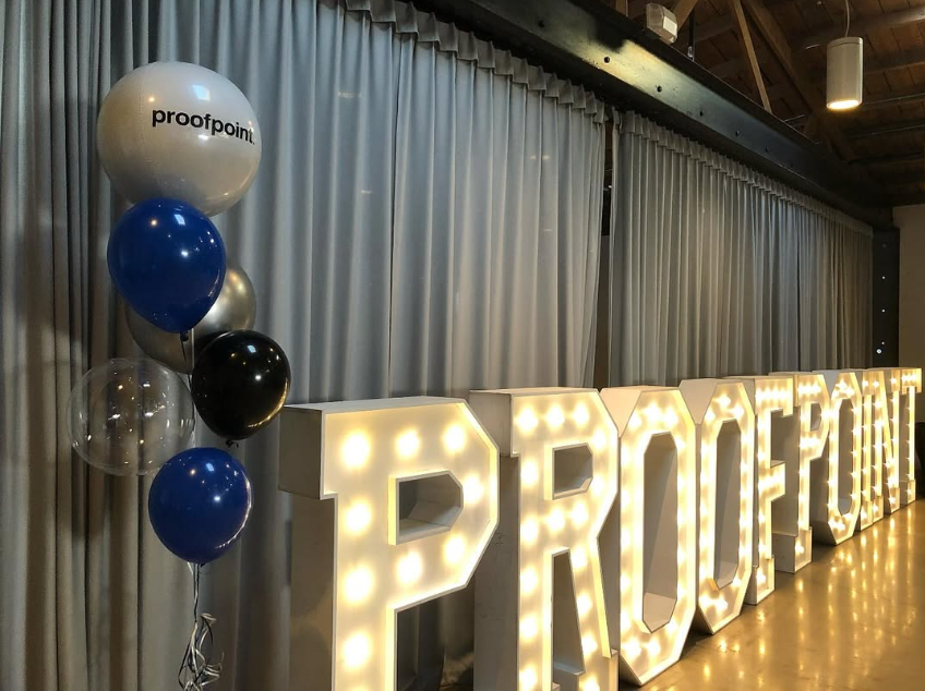 A large lighted sign in a room with balloons