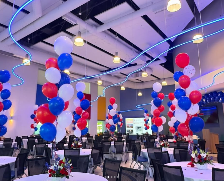 A large room with tables and chairs decorated with red white and blue balloons