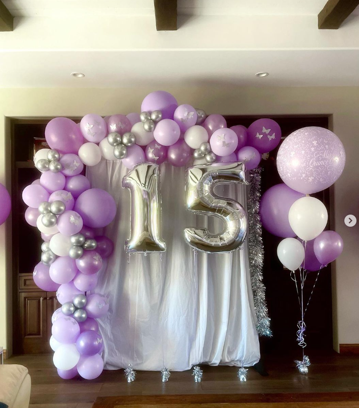 A room decorated with purple and silver balloons and the number 15