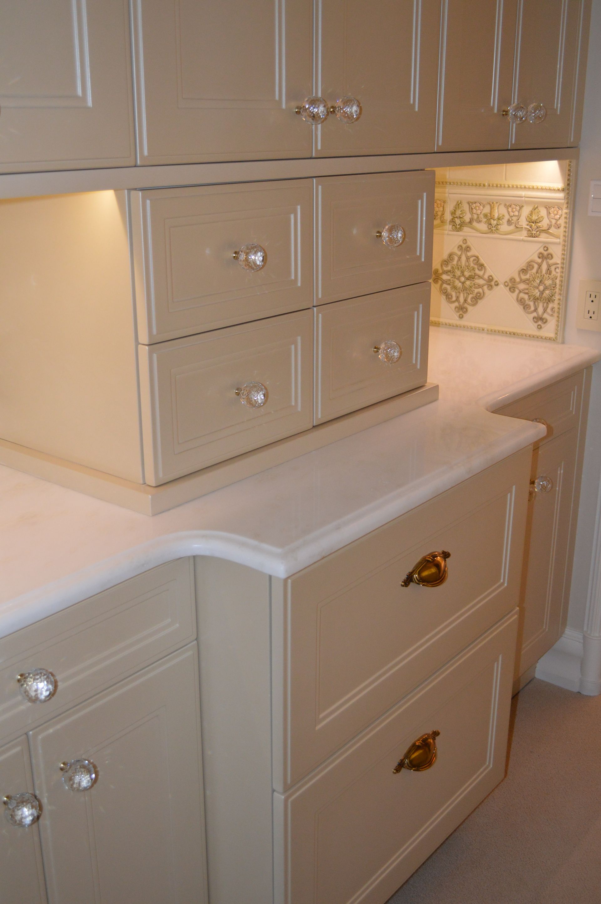 A kitchen with white cabinets and drawers with gold handles
