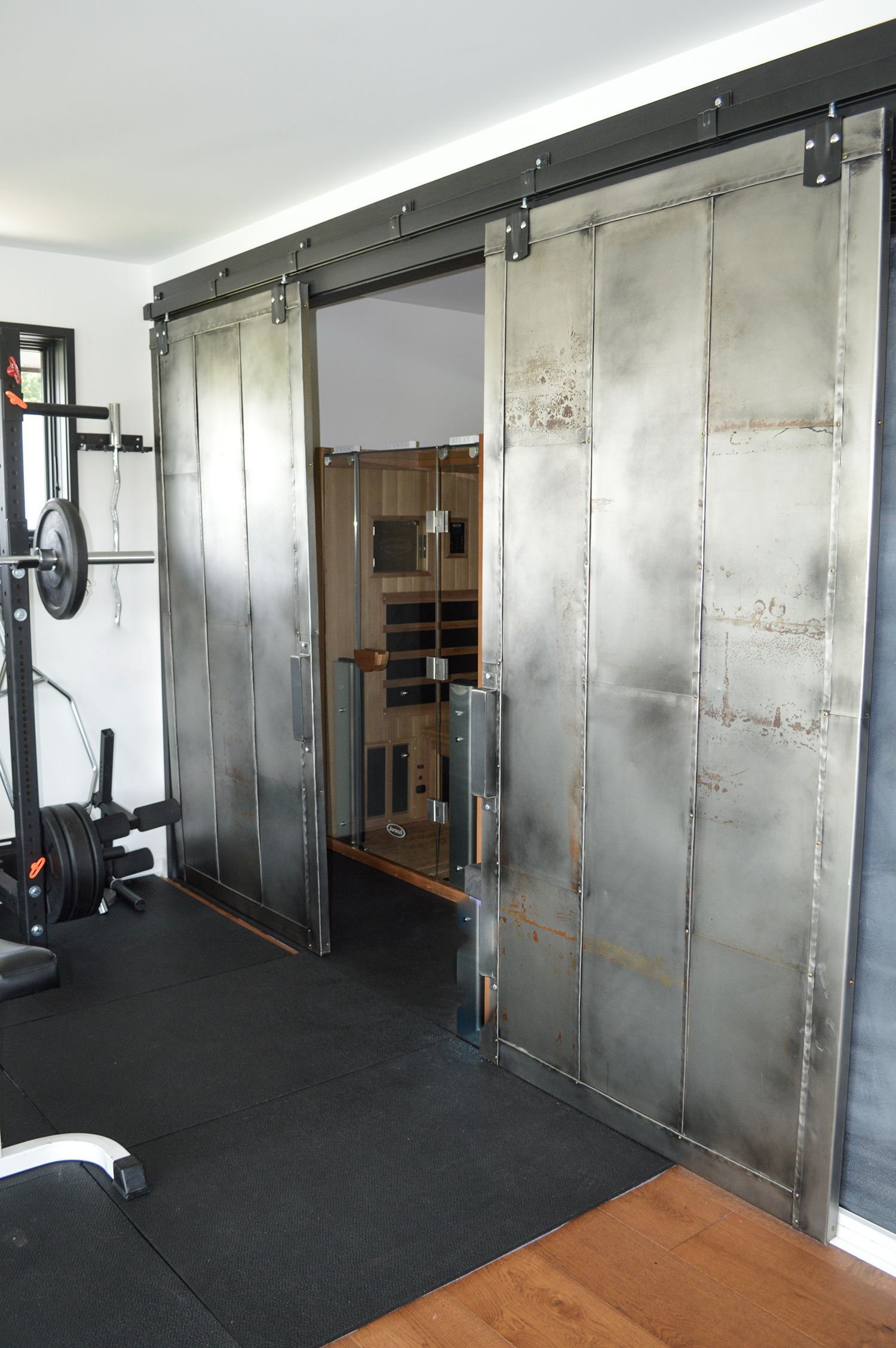 A gym with sliding barn doors and a barbell rack.