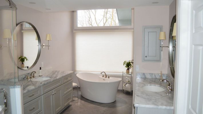 A bathroom with two sinks, a tub, a mirror, and a window.