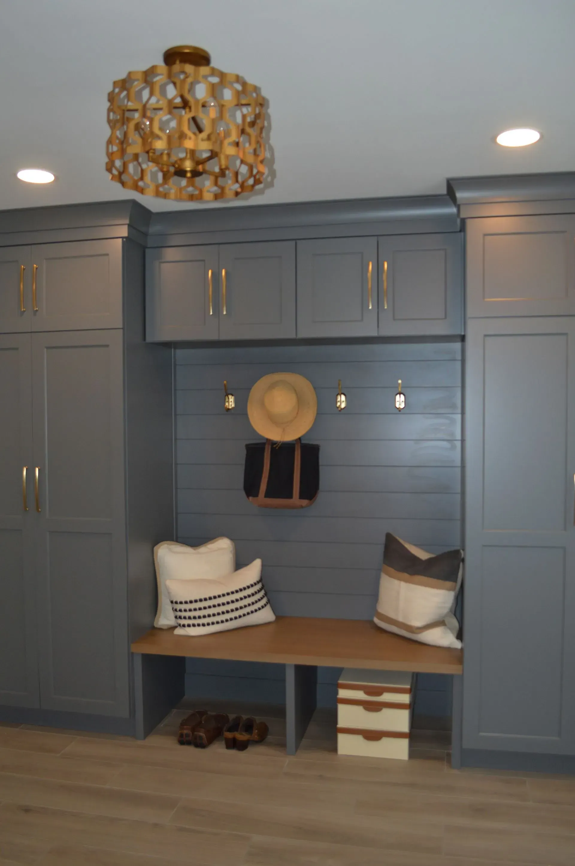 A room with a bench and a hat hanging on the wall.