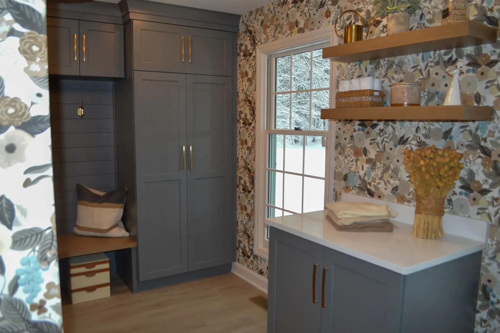 A laundry room with gray cabinets, shelves, and a window.