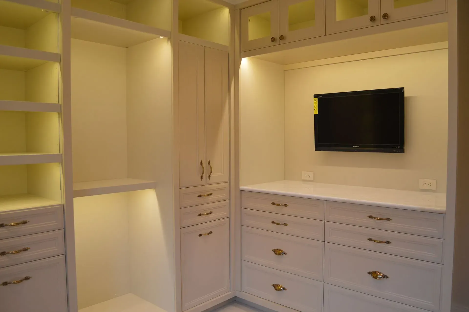 A walk in closet with a flat screen tv on the wall.
