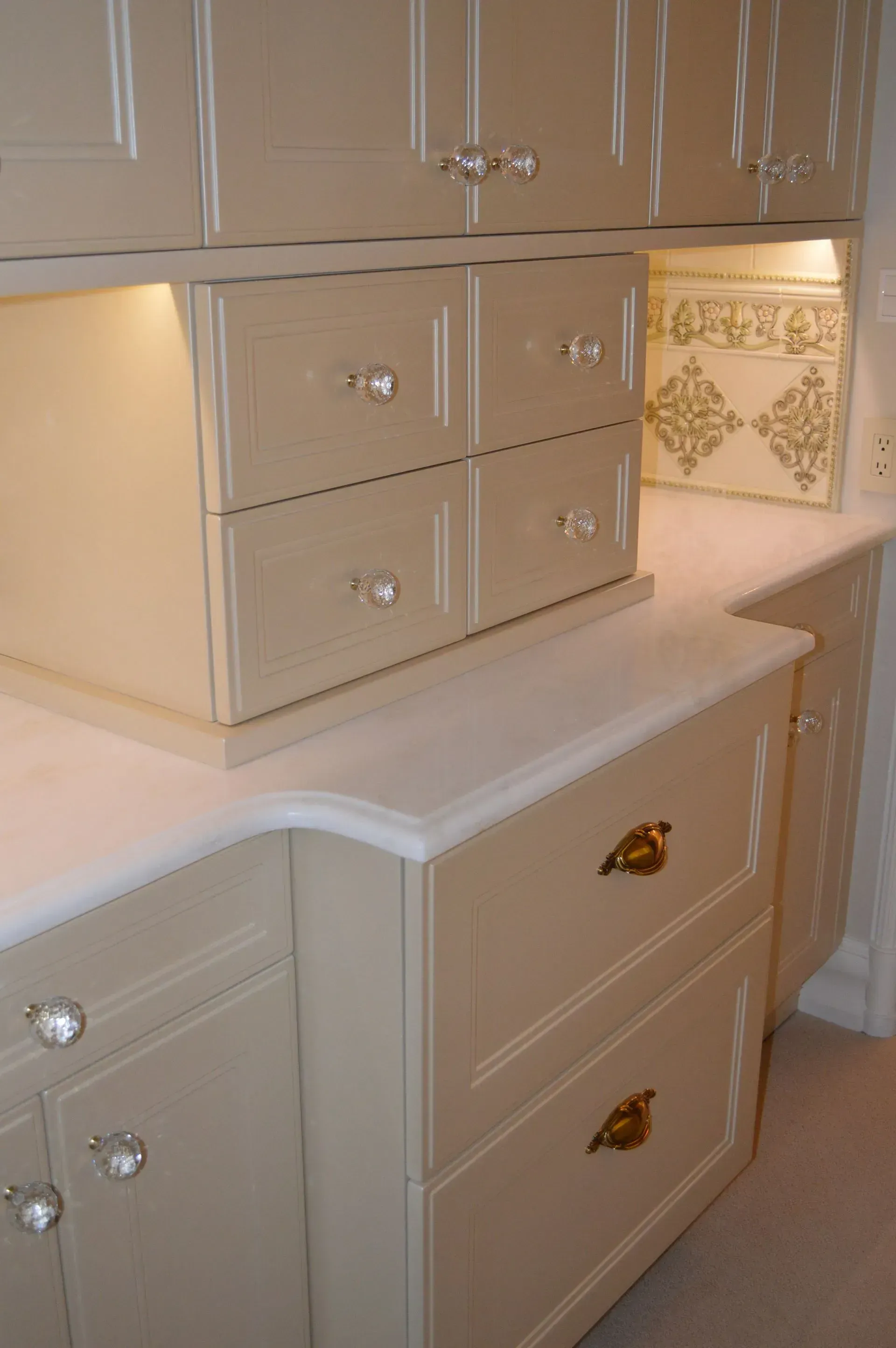 A kitchen with white cabinets and drawers with gold handles.