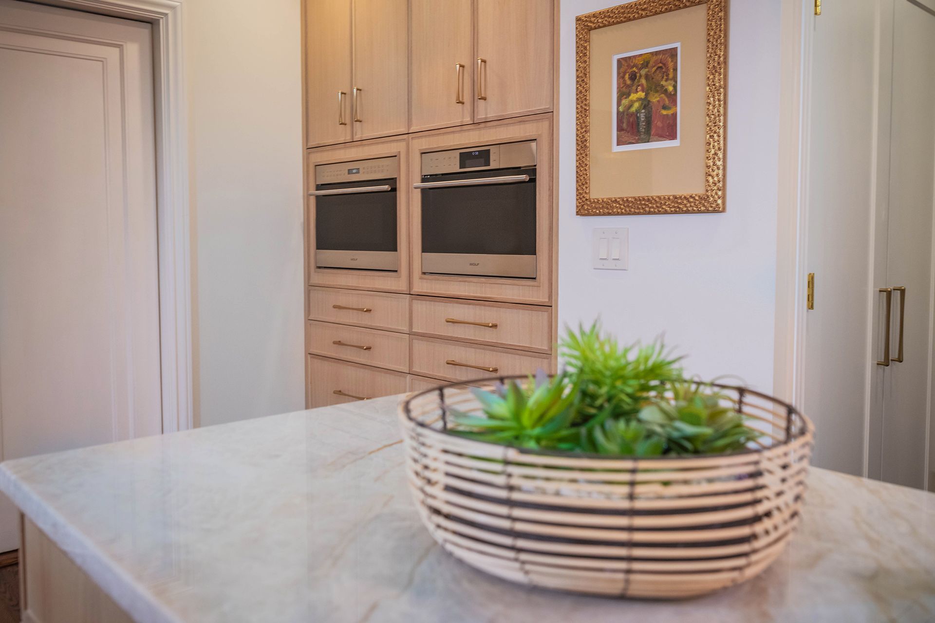 A bowl of plants is sitting on a counter in a kitchen.