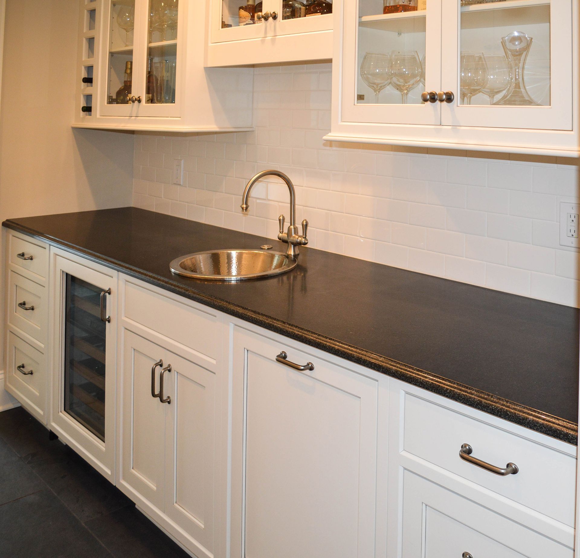 A kitchen with black counter tops and white cabinets.