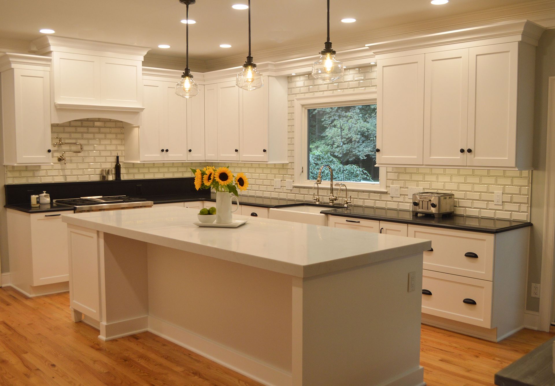 A kitchen with white cabinets, black counter tops, and a large island.