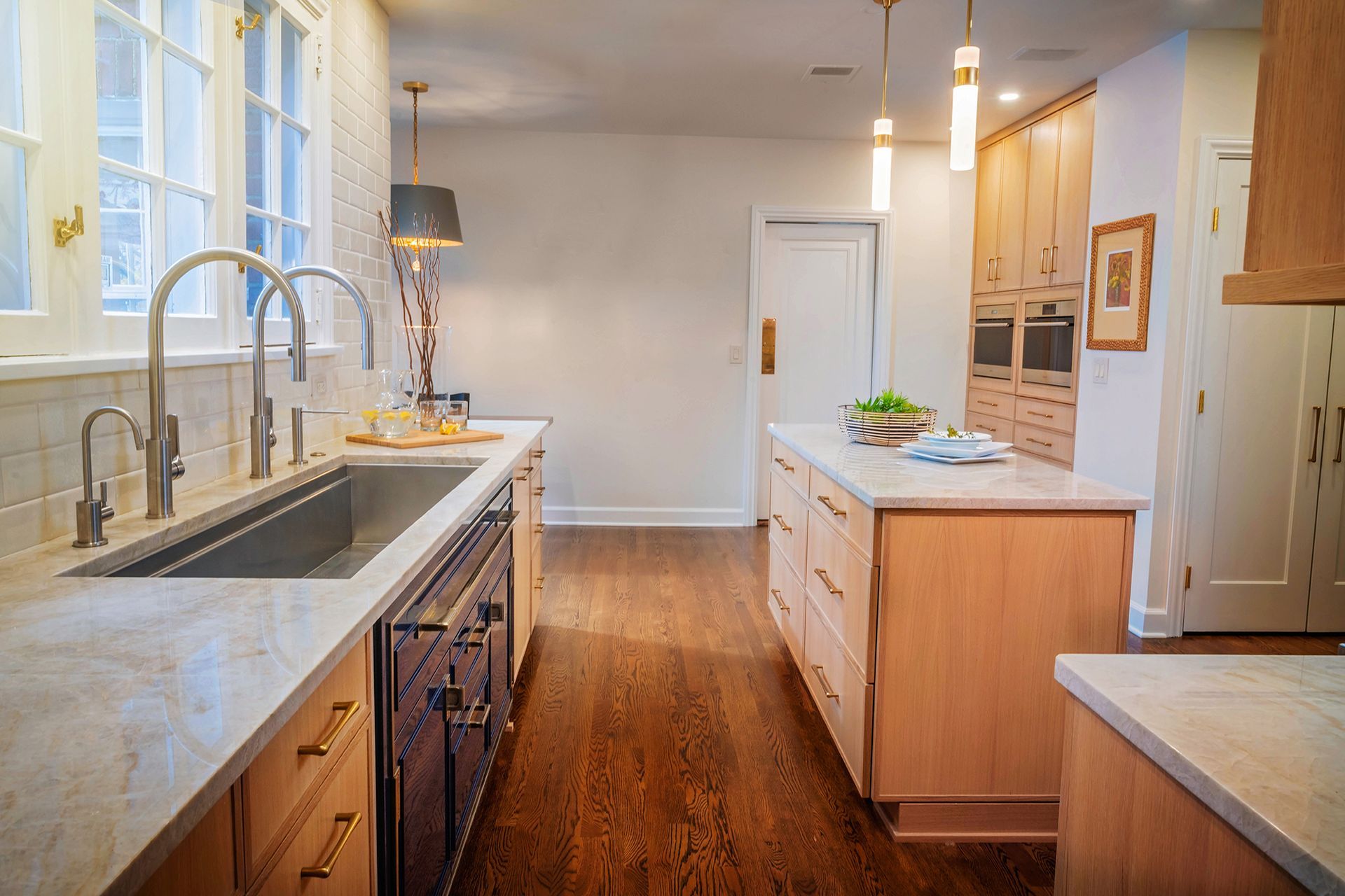 A kitchen with a large sink , wooden cabinets , granite counter tops and stainless steel appliances.
