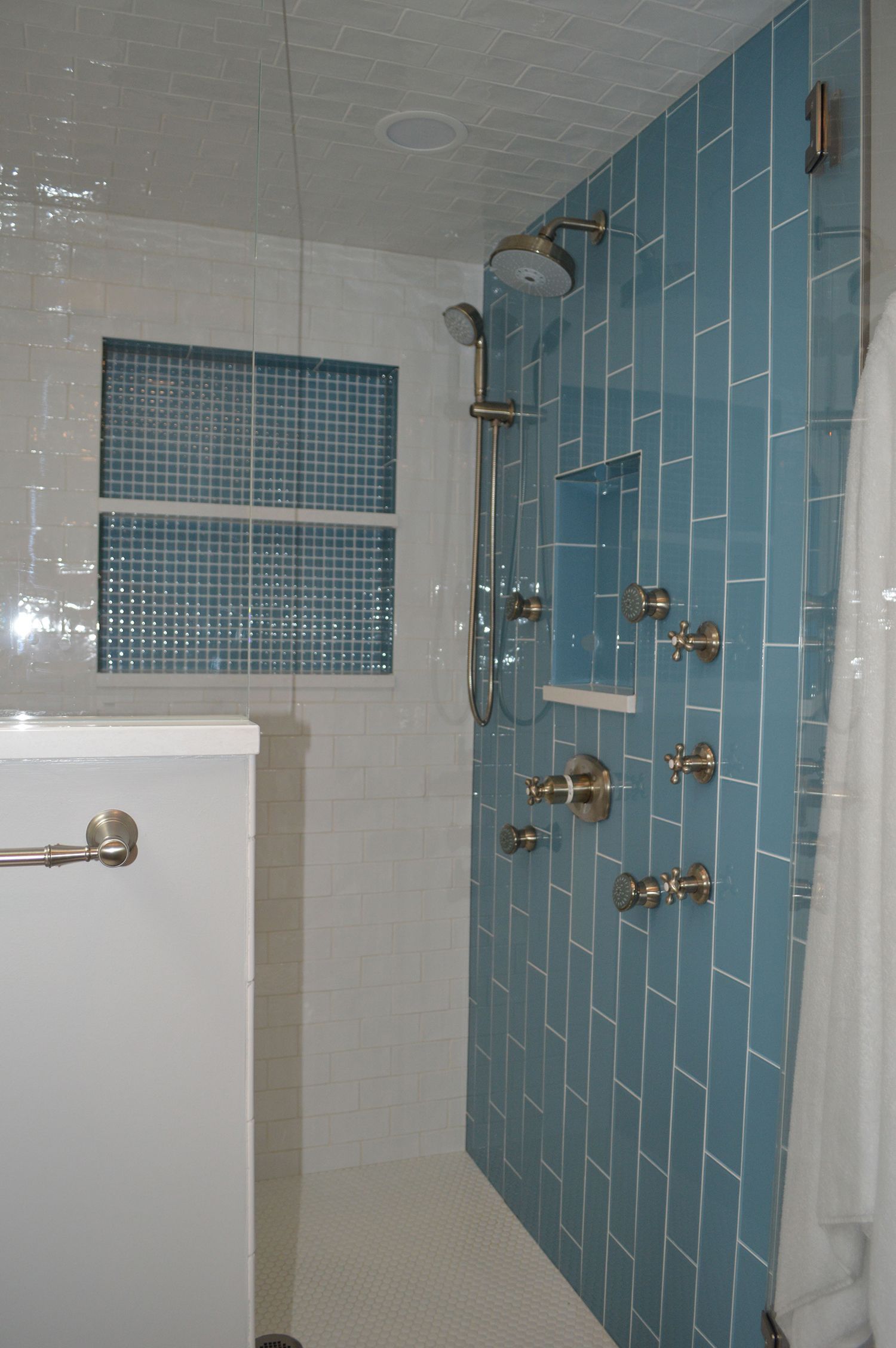 A bathroom with blue tiles and a shower head.