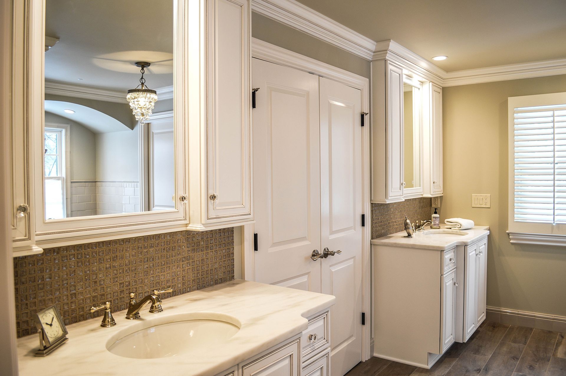 A bathroom with two sinks, two mirrors, and a window.