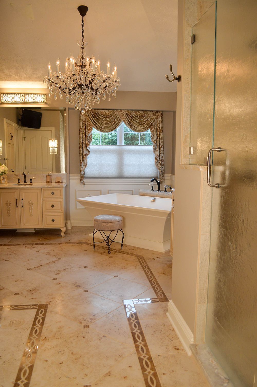 A bathroom with a tub, sink, mirror, and chandelier.