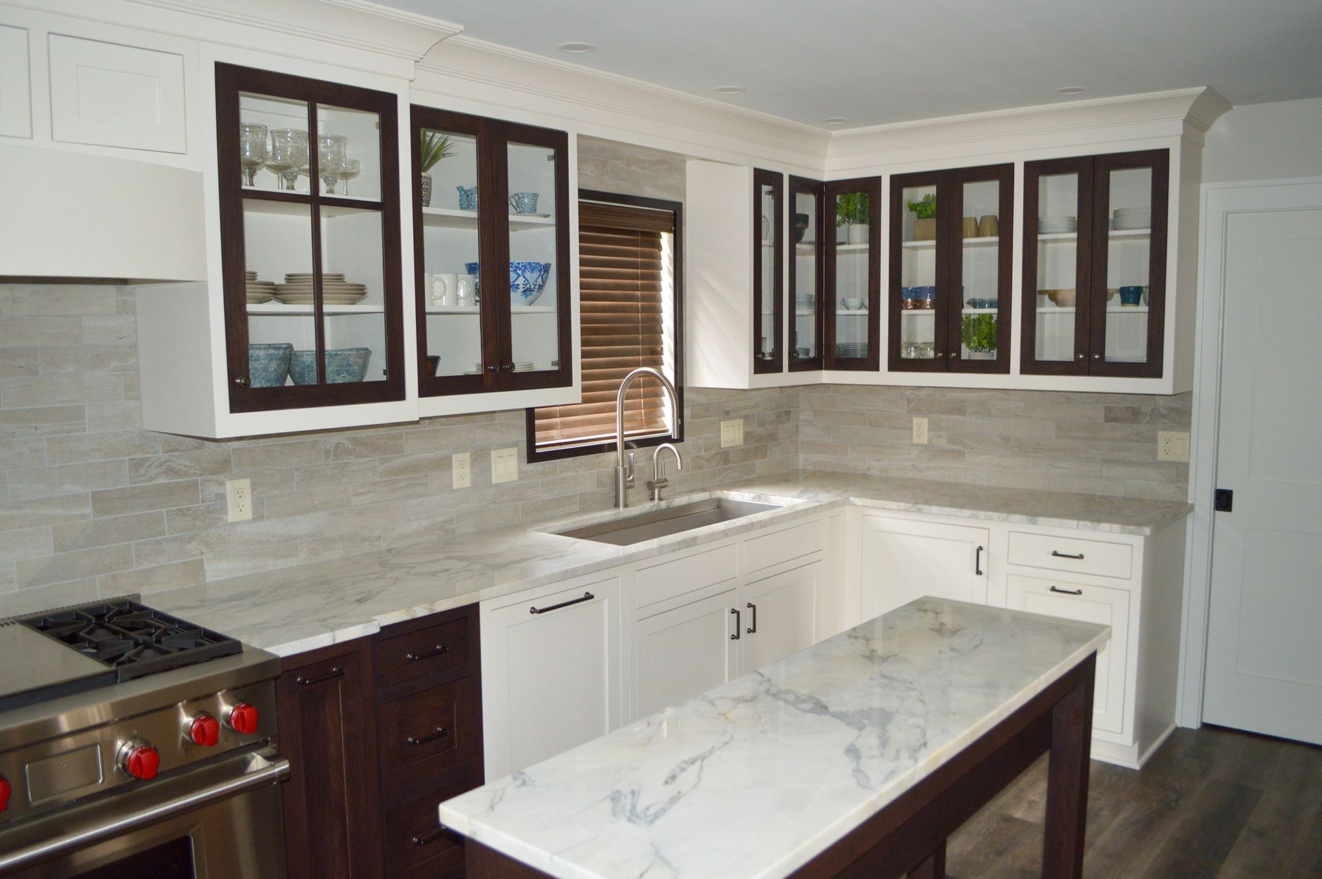 A kitchen with white cabinets, a stove, a sink, and a large island.