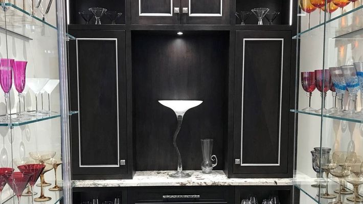 A cabinet filled with lots of glasses and a lamp