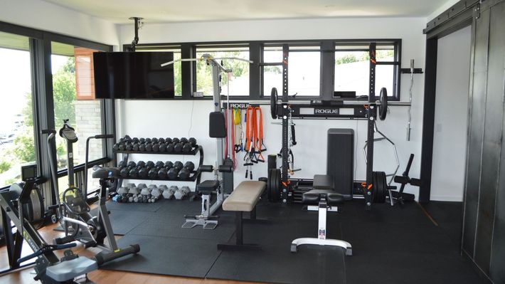 A home gym with a lot of exercise equipment and a flat screen tv.